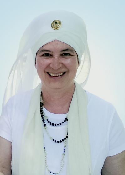 Headshot of Shanti Shanti Kaur smiling and wearing a white turban and white clothing.